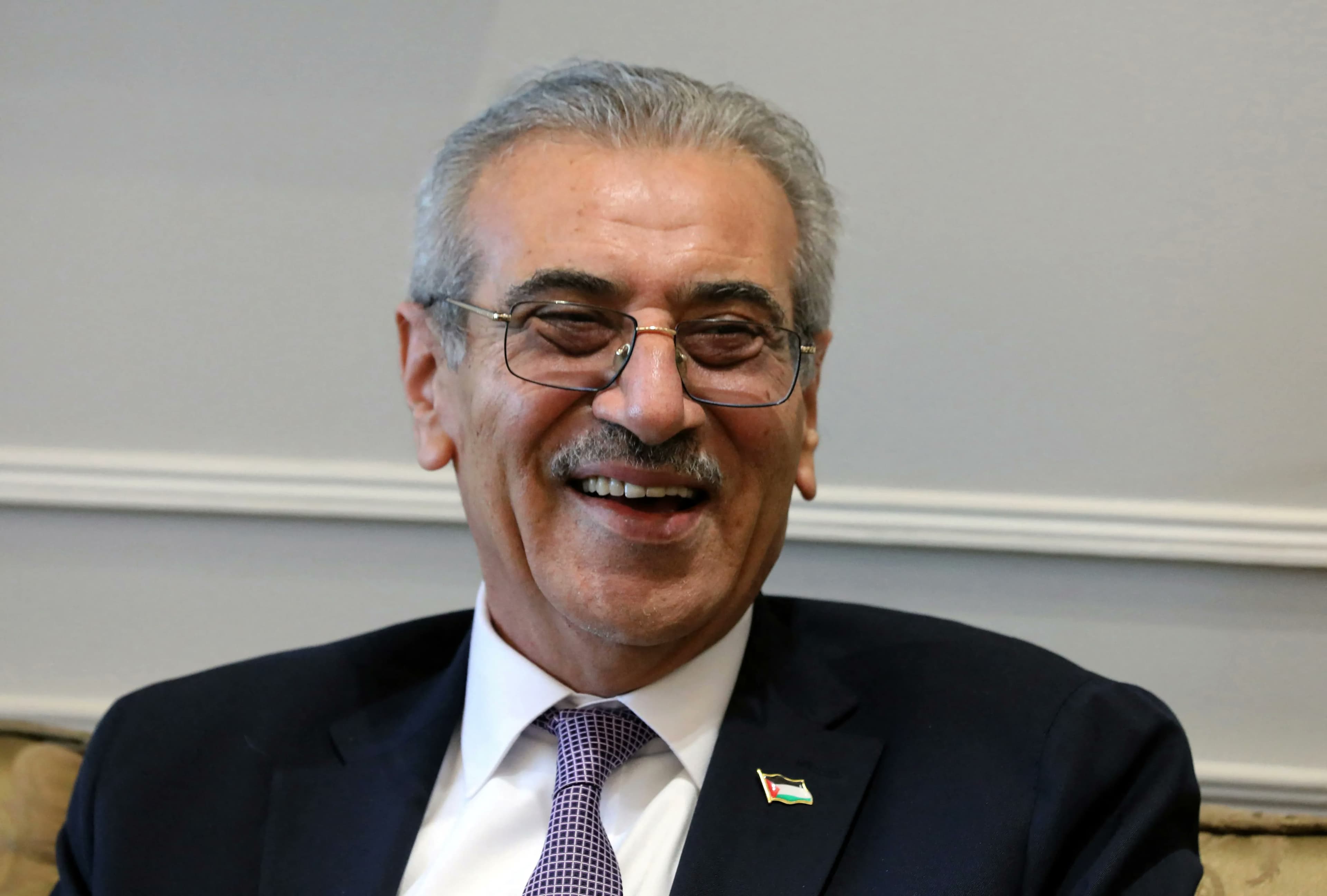 Ali Abdel Hamid Shaath, wearing glasses and a Palestinian flag lapel pin, laughs during a meeting.