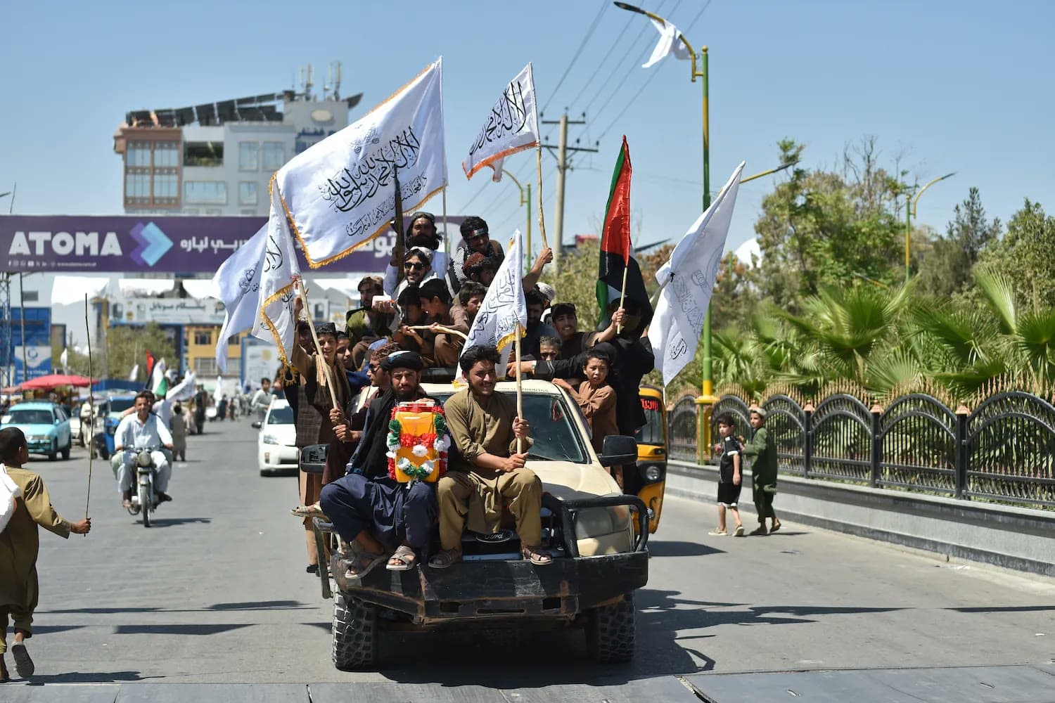 Taliban fighters and supporters wave white Taliban flags while riding a pickup truck through a street in Kabul, Afghanistan.