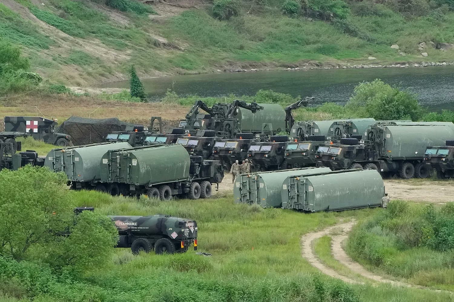 U.S. military tanker trucks and vehicles parked in a field near a river during a joint U.S.-South Korea military exercise.